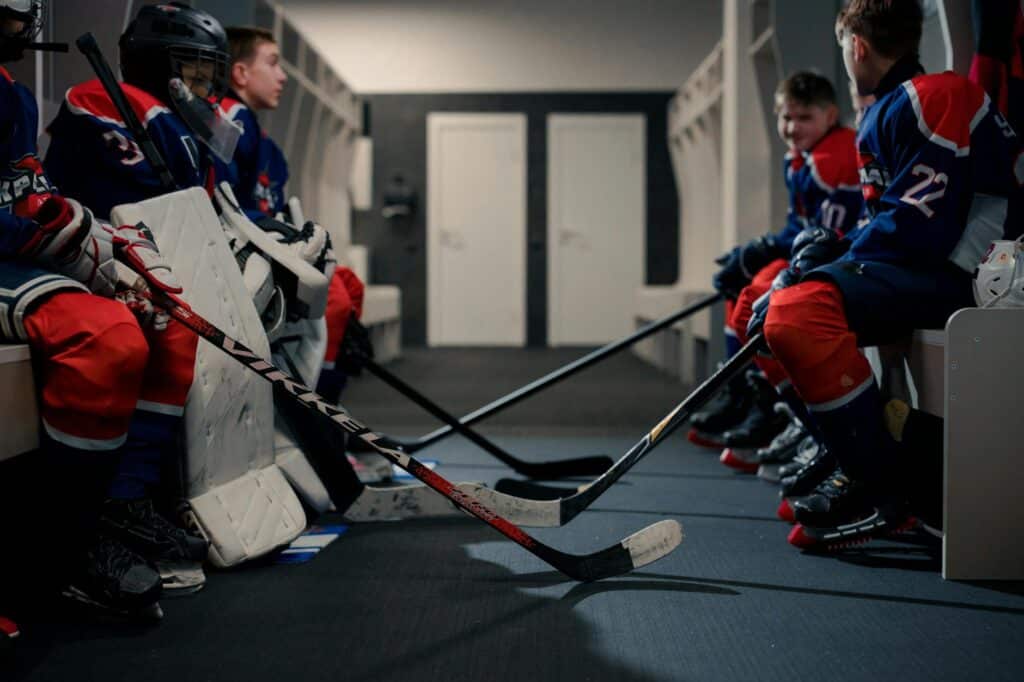 a group of boys in hockey gear sitting in a locker room