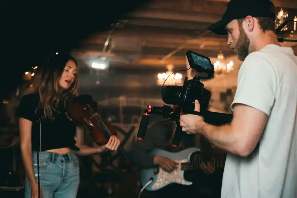 a man holding a camera and a woman playing a violin